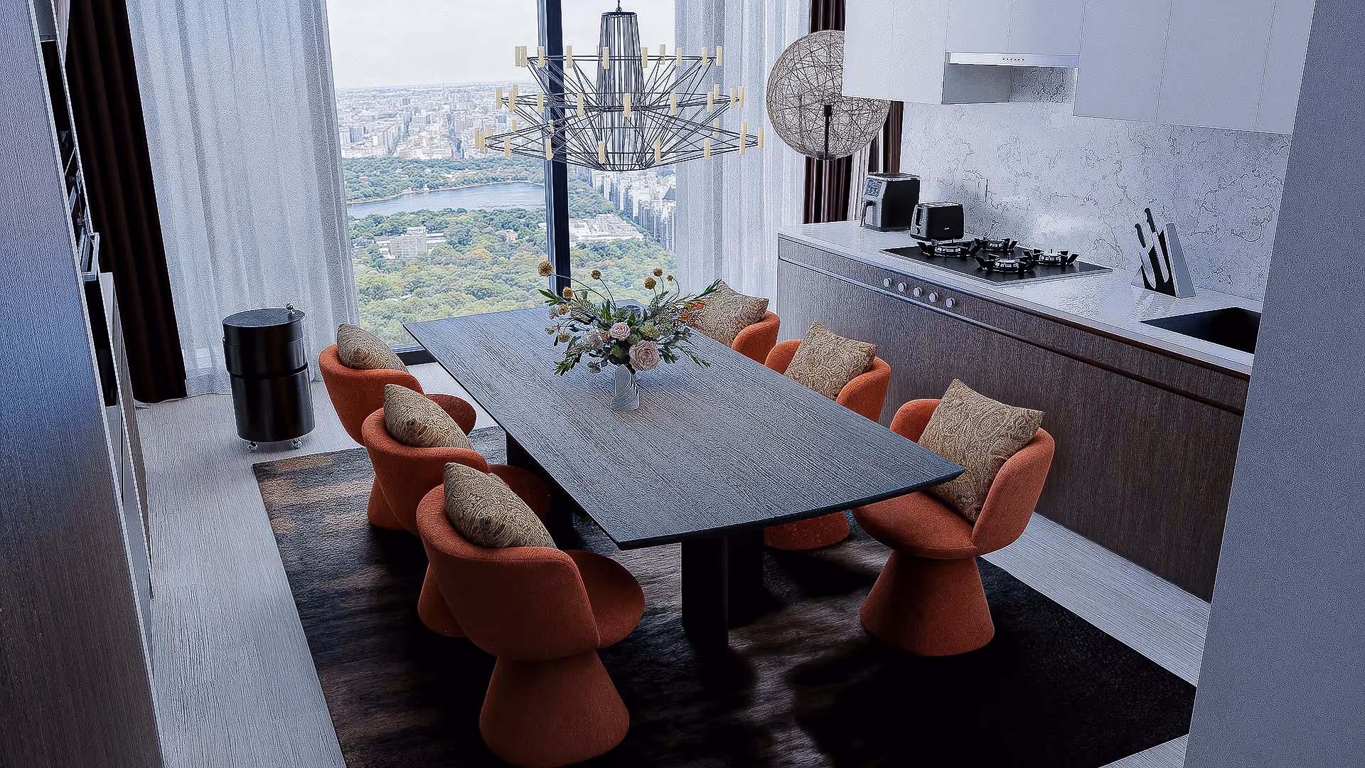 This dining area is designed around a sculptural axis, where function meets visual composition. A large abstract artwork anchors the space, while panoramic windows bring in natural light and frame the cityscape like living art. A glass-top table maintains visual openness, and curved chairs add rhythmic form that complements the central artwork. The palette ivory, deep green, and black conveys a refined calm with architectural depth. On one side, a Steinway grand piano grounds the space with elegance; on the other, a black console and sculptural objects create vertical balance. Overhead lighting is precisely positioned to highlight both art and dining, completing the scene with a softly immersive atmosphere.