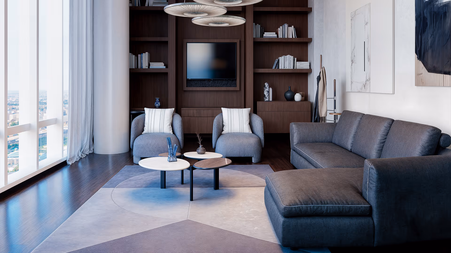 This living room features an L-shaped sofa paired with two lounge chairs, arranged around a centrally positioned round coffee table to create a conversational, face-to-face layout. The configuration encourages natural interaction between users, while all seating is oriented toward the center establishing a focused spatial composition without visual distraction.
