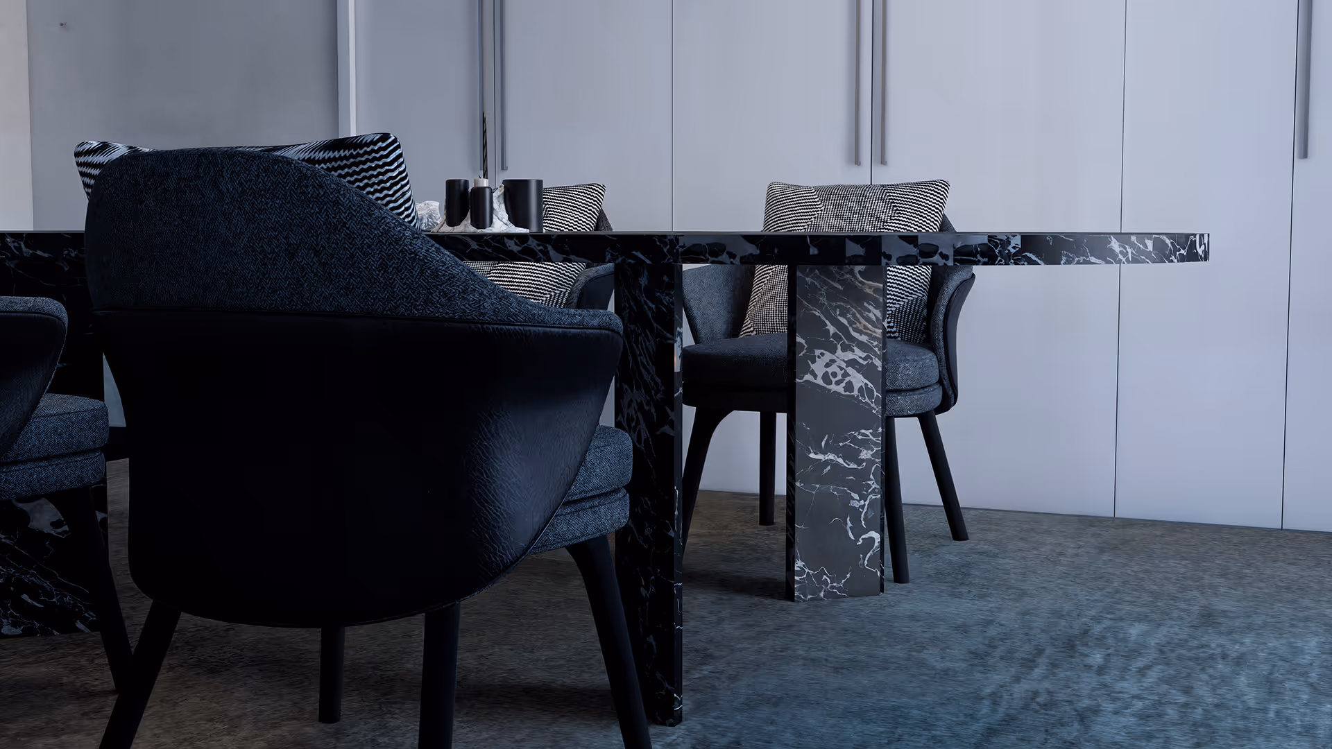 This dining space embraces a deep monochrome palette navy, black, and cool gray balanced through tonal variation and material contrast. The black marble table anchors the room with bold veining that introduces movement, while textured chairs and striped cushions add softness and rhythm. Glossy and matte finishes are thoughtfully layered to create a refined atmosphere that feels both composed and visually dynamic.