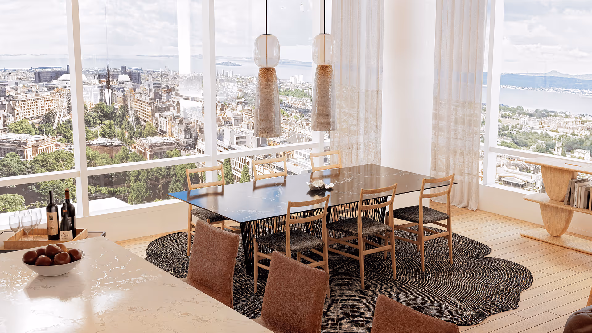 This dining space is thoughtfully arranged along expansive windows to maximize natural light and views, while the organic rug and sculptural lighting enhance the room’s rhythm and aesthetic harmony. It reflects a modern lifestyle that balances functionality with emotional resonance.