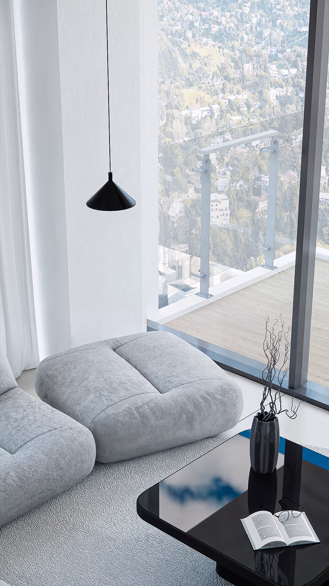 A detail view reveals the dialogue between form and function. The oversized floor cushion and black gloss coffee table suggest comfort and clarity, while natural light creates shifting shadows that animate the minimalist composition.