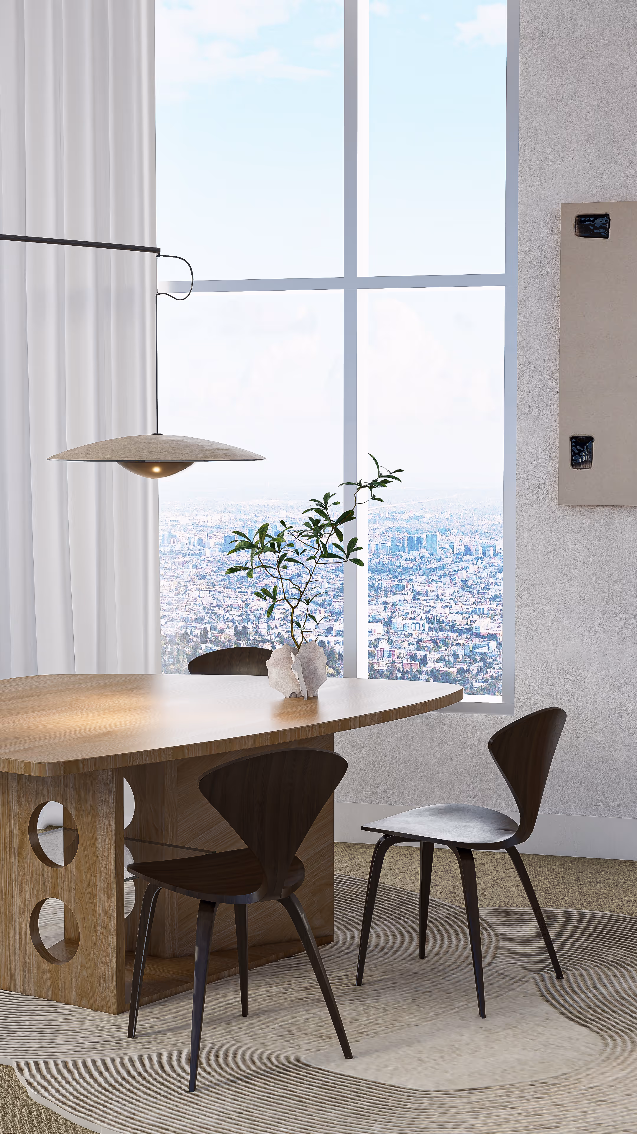 From this angle, the sculptural clarity of the furniture takes center stage. The table’s soft curves and tactile wood grain contrast gently against the panoramic city view outside. Placed as the focal point, the ceramic vase and its sprouting branches bridge the line between natural stillness and artistic expression.