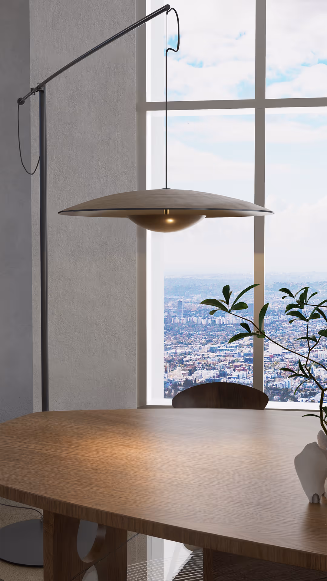 A sculptural pendant light hovers gently above the asymmetric wood table, casting a soft, ambient glow. The low-set chairs in dark stained wood offer a grounded feel, while the singular organic vase brings artistic intimacy to the setting. Behind, sheer curtains diffuse daylight into the space, blurring the outside cityscape into a tranquil backdrop.