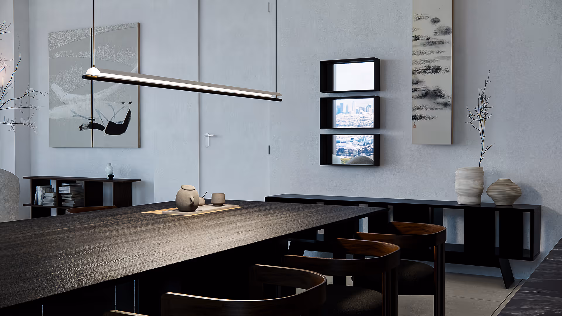 In this dining space, tradition meets quiet modernism. A minimalist pendant light floats above a richly grained blackwood table, while monochrome artworks and ceramics along the wall add layers of curated stillness. The scene invites slow meals, long conversations, and thoughtful presence.