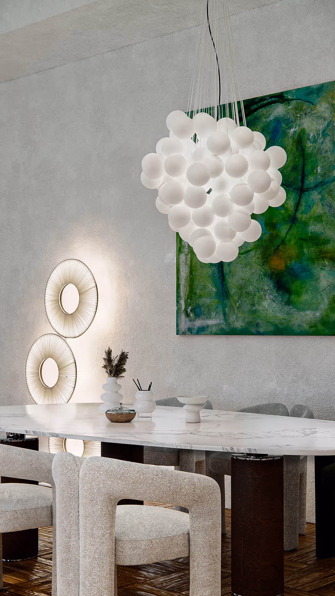 Roche Bobois' Cactus Floor Lamps softly glow against the textured wall, echoing the orb-like forms of the chandelier above. The contrast between smooth, glossy finishes and textured, matte materials establishes a delicate tension that elevates the overall ambiance.