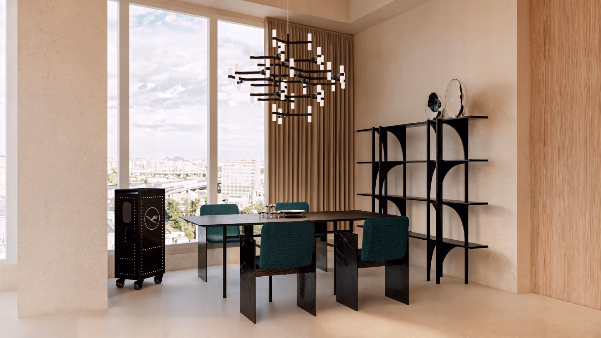 A refined palette of charcoal black and blue-green adds depth to the space while acting as a visual anchor that naturally draws the eye. The furniture, chosen for its sculptural and contemporary silhouettes, departs from conventional forms to strike a harmonious balance between functionality and artistic expression. Curved sofas and architectural chairs are positioned like art installations, transforming the space into a gallery-like experience.
